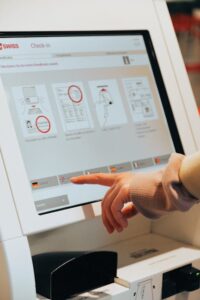 Hand interacting with airport self-service kiosk for check-in.